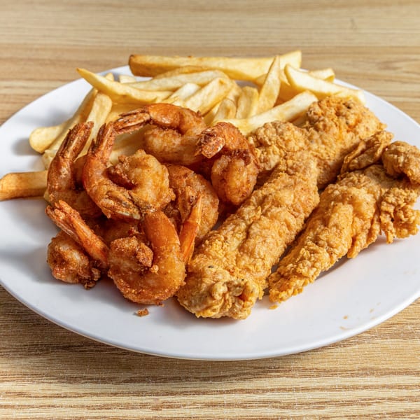 A white plate holds fried shrimp, fried fish, and a pile of golden french fries.