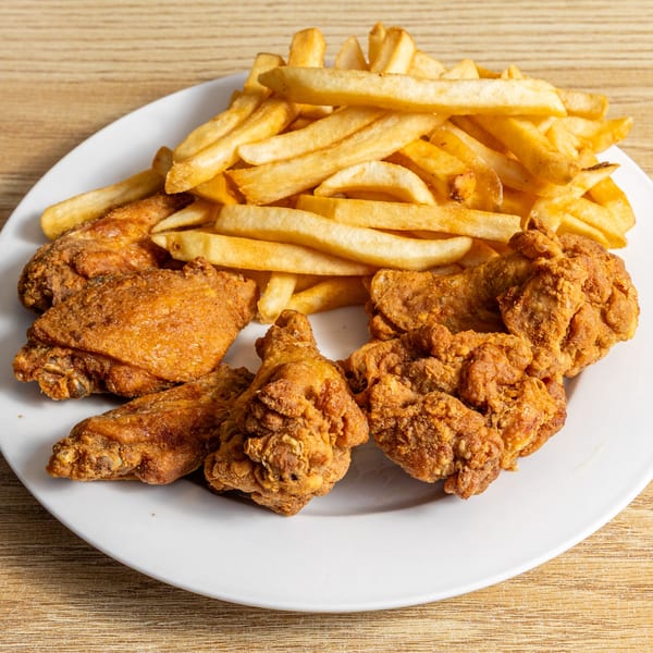 Golden-brown fried chicken pieces and crispy french fries served on a white plate.
