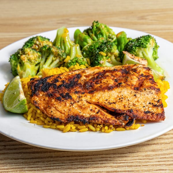 Grilled Red Snapper with yellow rice, broccoli, and a lime wedge on a white plate.